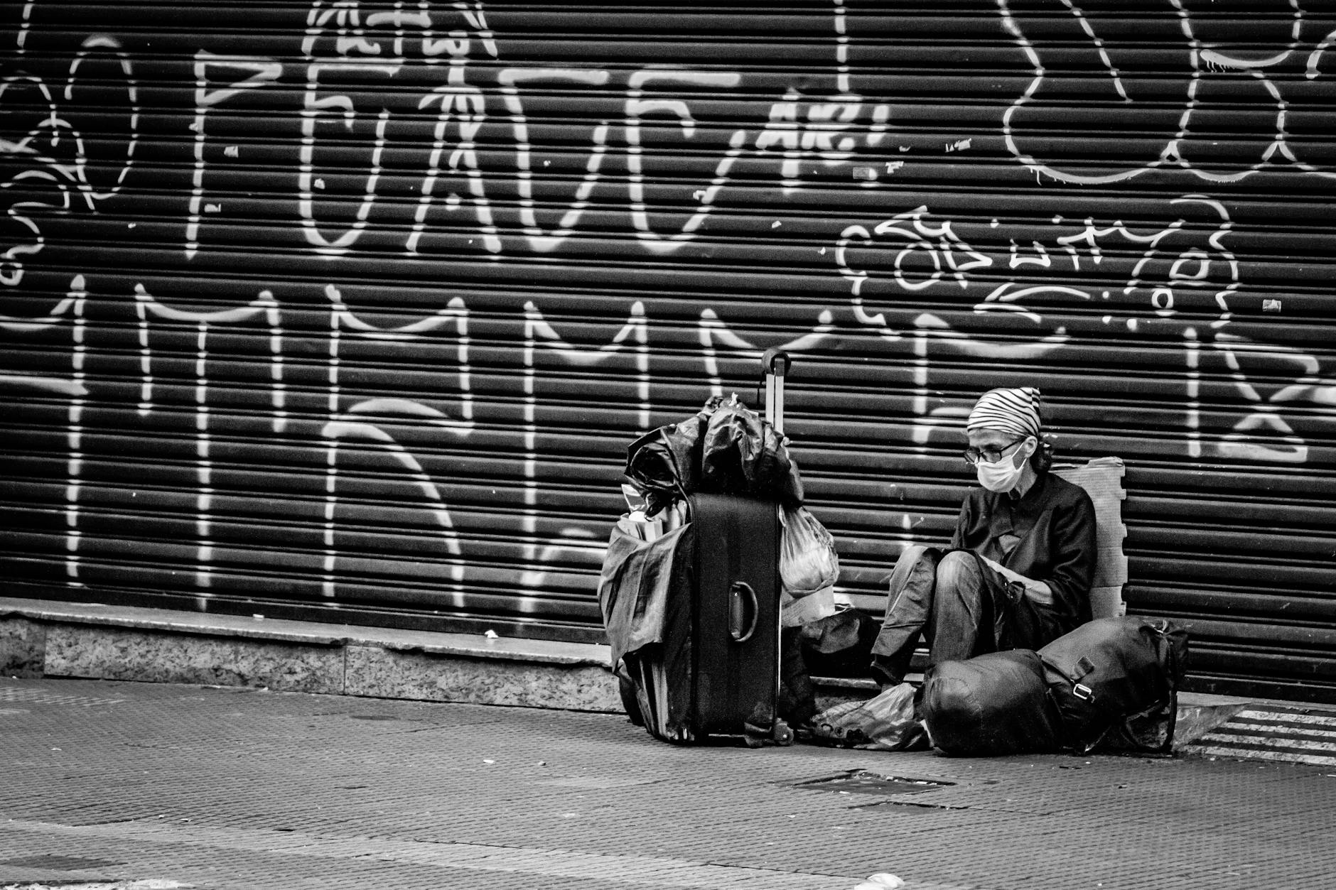 unrecognizable tourist in mask with suitcase near graffiti wall