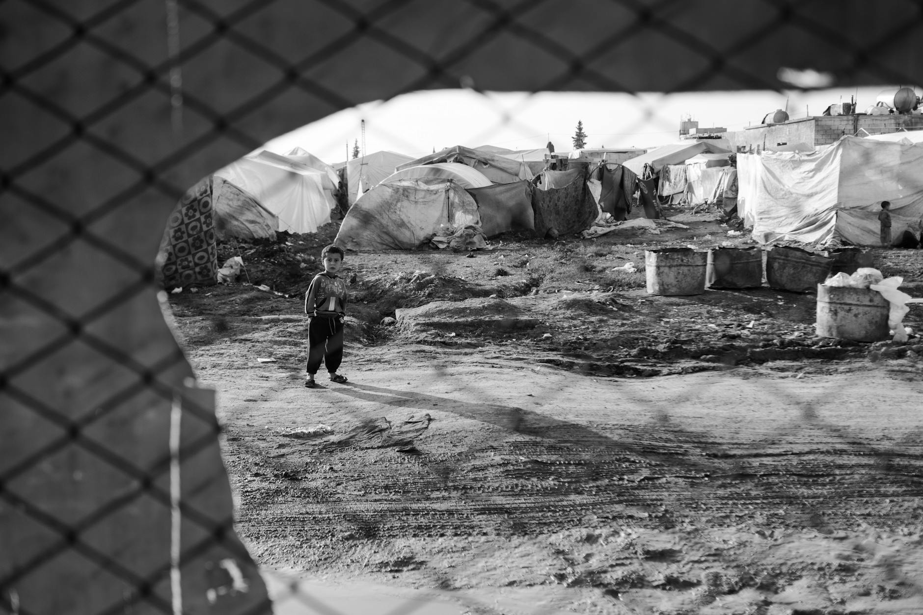 child standing in syrian refugee camp amidst tents